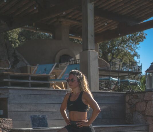 여름철 운동 후 스트레칭 루틴 woman in black sports bra and black shorts sitting on concrete bench during daytime