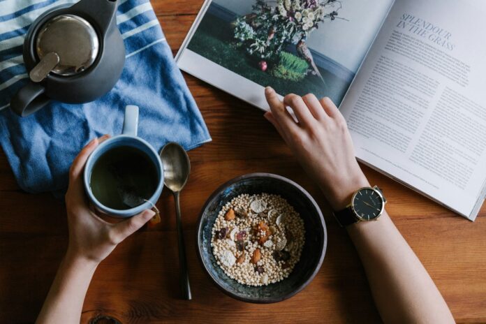 Photo by THE 5TH person holding blue ceramic mug and white magazine