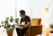 “에어컨 바람만 쐬면 머리가 띵해요”… 초여름 두통, 냉방병일 수 있습니다 a man sitting in a chair wearing a face mask