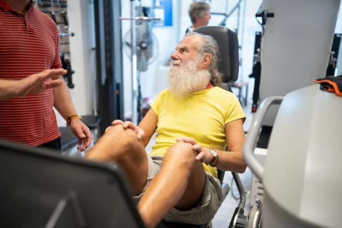 a man with a white beard sitting in a gym