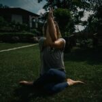 디톡스 요가: 비틀기 동작으로 체내 독소를 제거하는 ‘장 청소’ 가이드 a woman sitting on the ground with her hands in the air