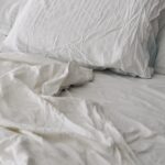 현대인의 숙면 트렌드, 실생활에서 실천하는 ‘슬기로운 수면 루틴’ A rumpled white duvet and pillows on a bed.