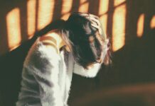 만성피로, 단순한 피로 아냐…지속되면 질병 신호일 수 있다 woman leans on wall in white fur jacket docking her head while holding it using her leaf hand