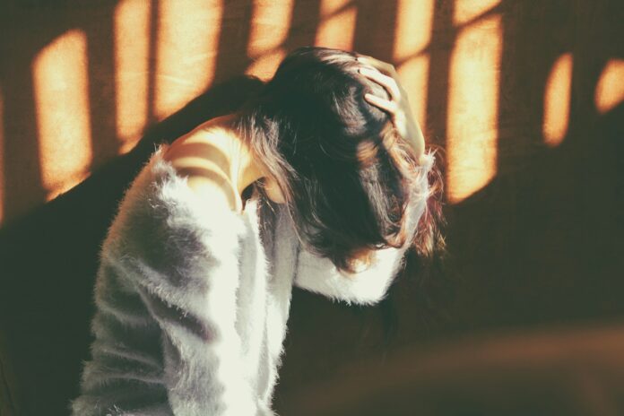 Photo by Carolina Heza woman leans on wall in white fur jacket docking her head while holding it using her leaf hand