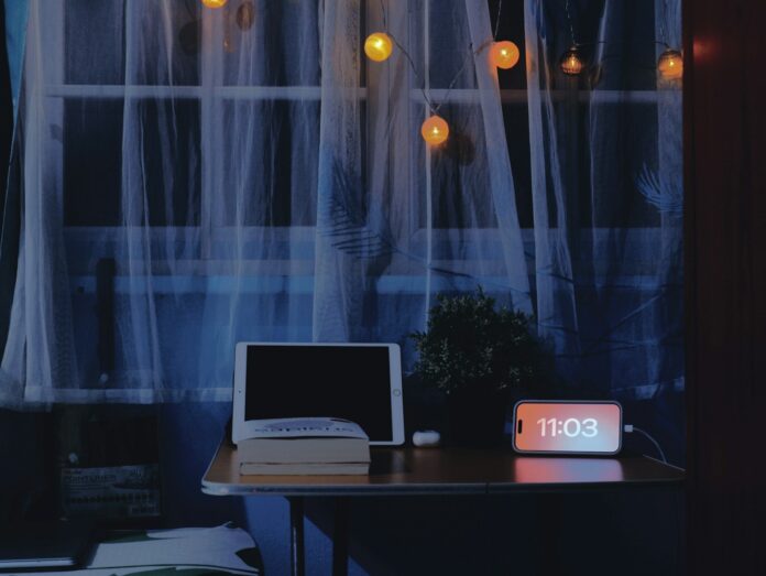 Photo by Truong Tuyet Ly Desk with tablet, book, and digital clock at night.