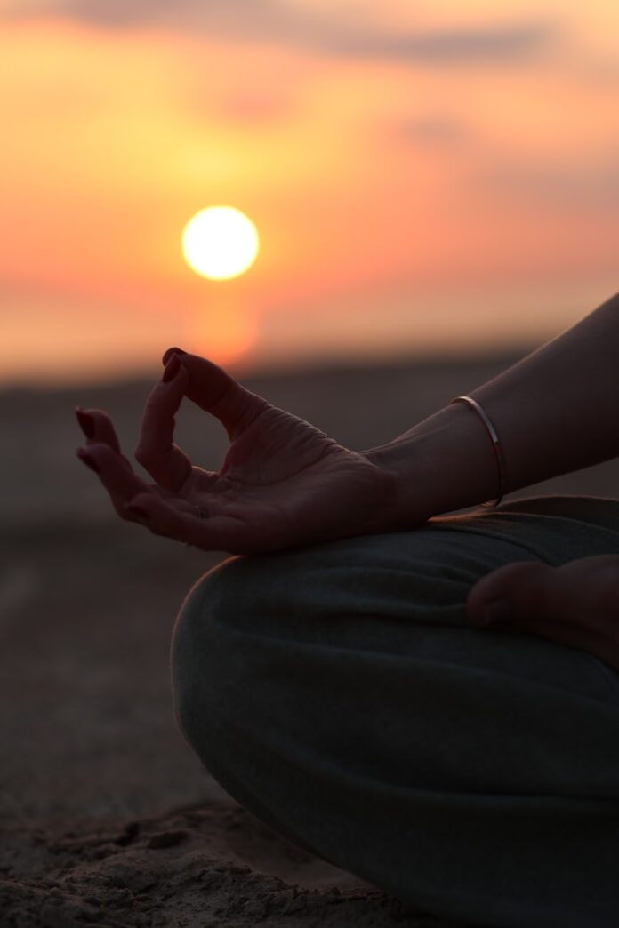 Photo by Raspopova Marina A person sitting in a yoga position with the sun setting in the background