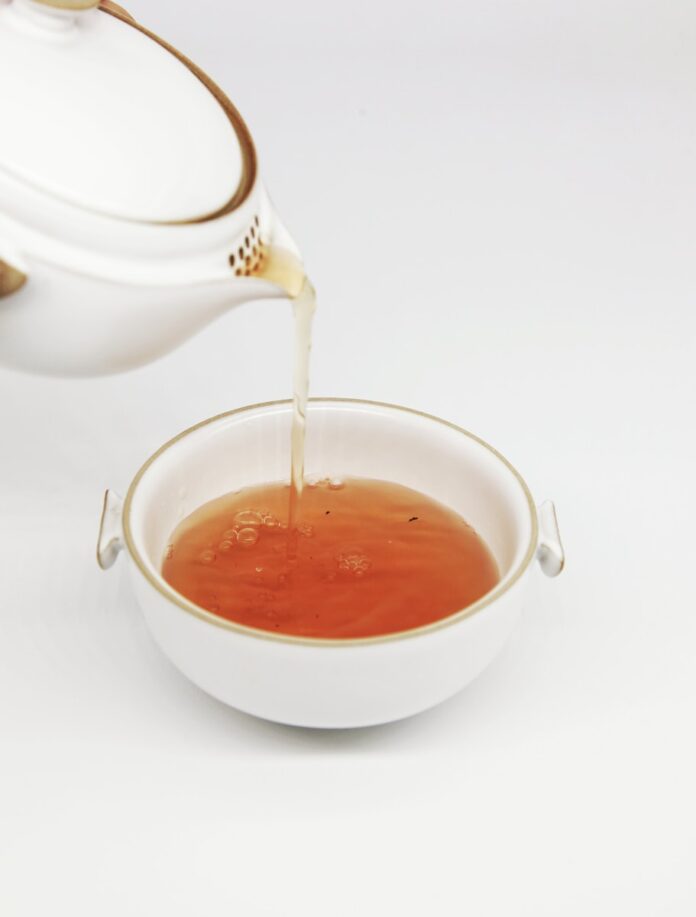 Photo by CHI CHEN tea pours into white teacup